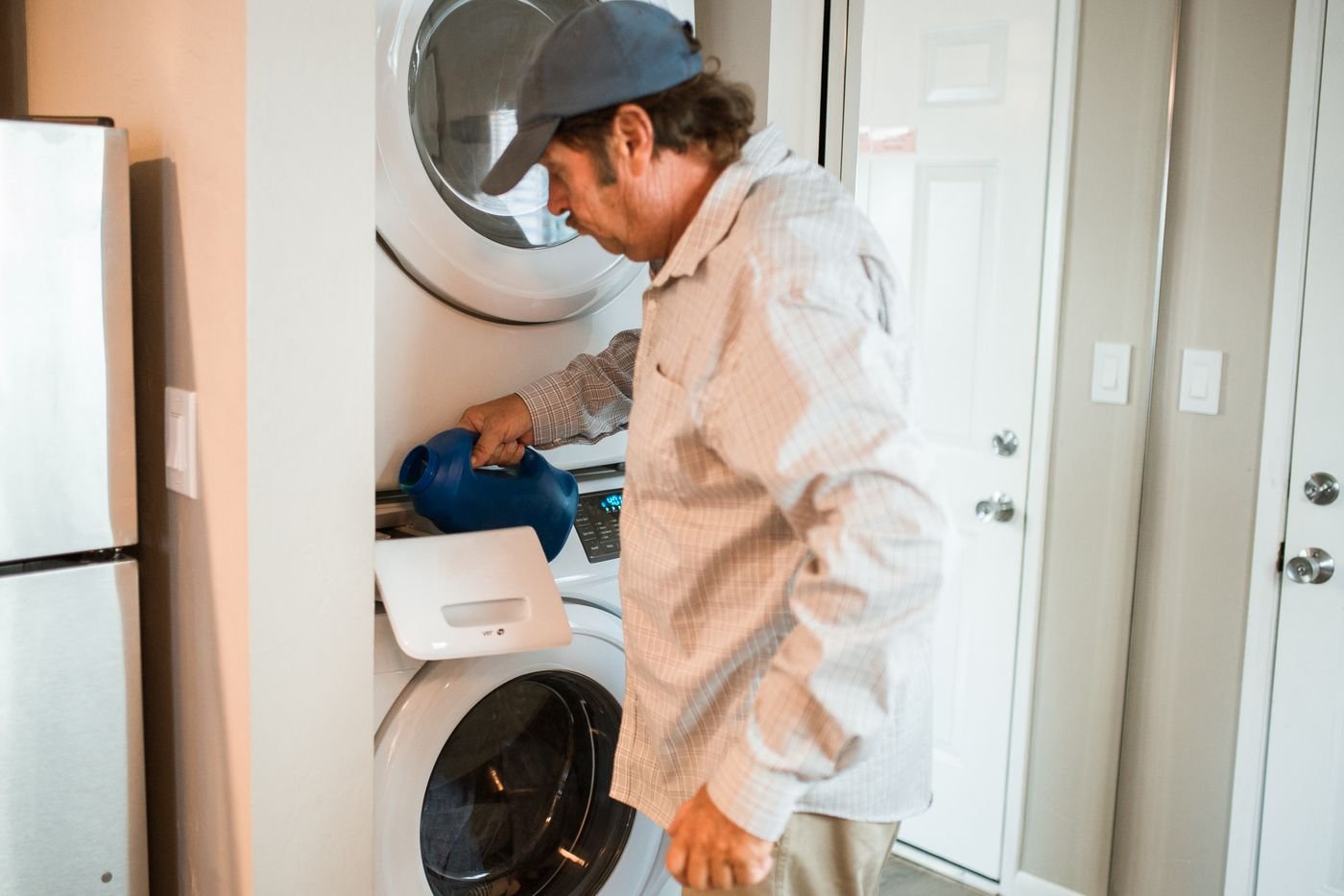 Technician servicing a home washing machine during maintenance visit